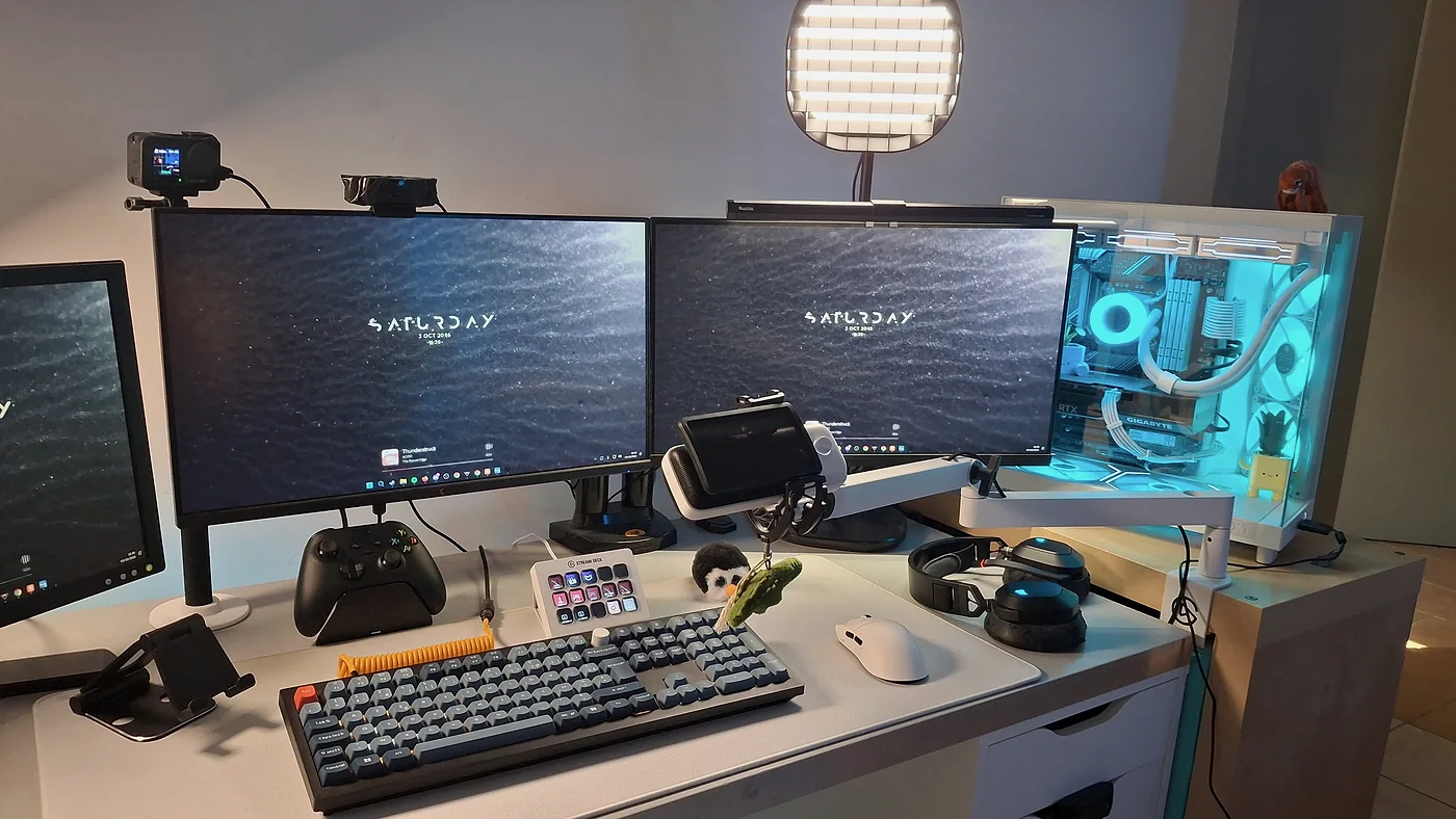 Les deux écrans principaux avec la caméra d'action et une webcam posées dessus, une lumière de stream au-dessus et le PC à droite.