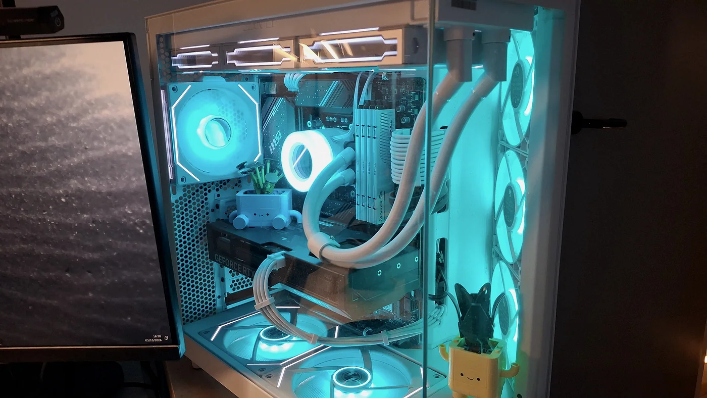 Gros plan sur l'intérieur du PC : carte graphique, refroidissement liquide blanc et ventilateurs bleu clair, avec de petites plantes en pot.